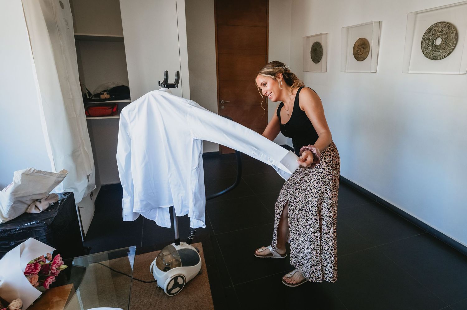 Woman shaking out a white dress shirt in a modern hotel room.