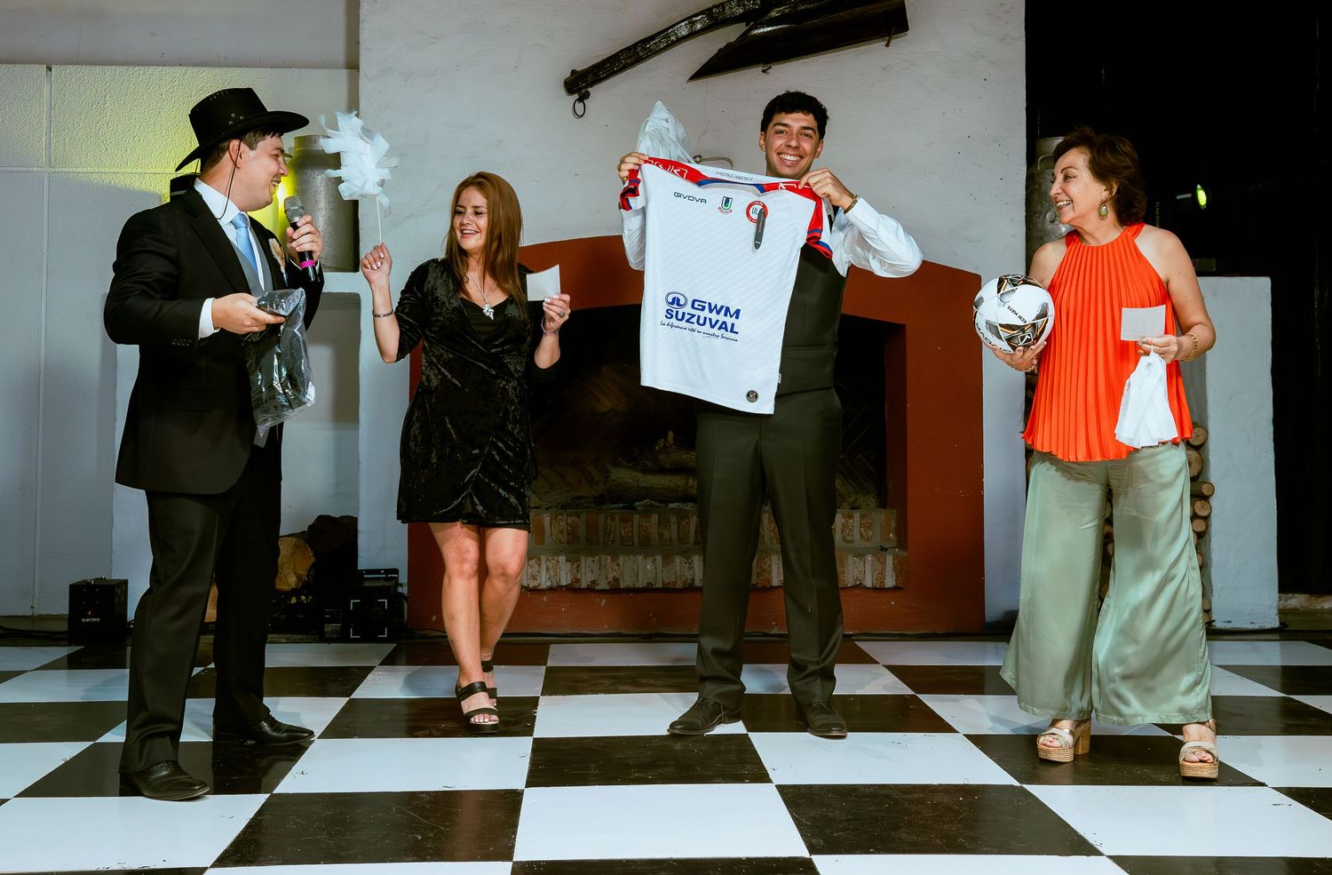 Wedding guests display soccer jersey on checkered dance floor at festive reception.