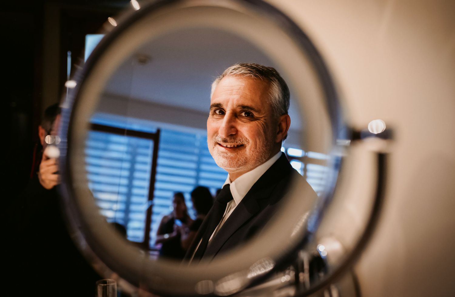 Professional man in suit reflected in circular mirror, captured in elegant hotel room setting.
