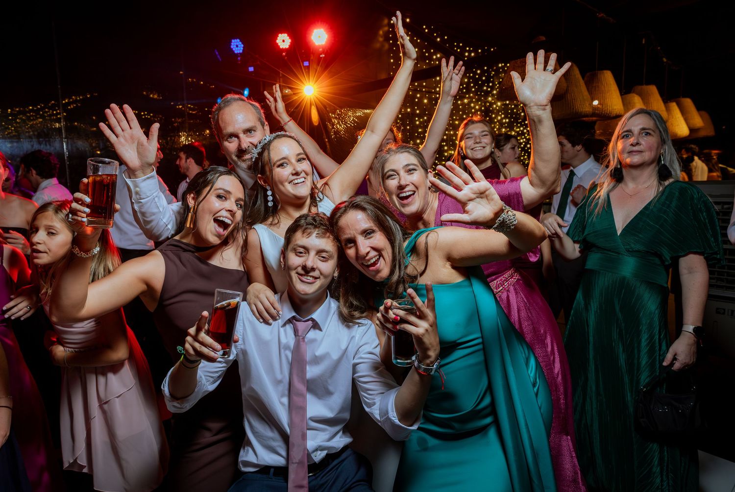 Happy wedding guests posing together for a selfie on a lively dance floor at a reception.