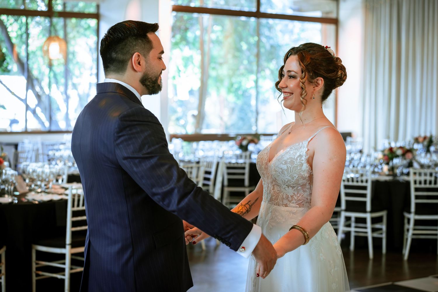 Newlyweds hold hands and share a tender moment on the dance floor at their wedding reception.