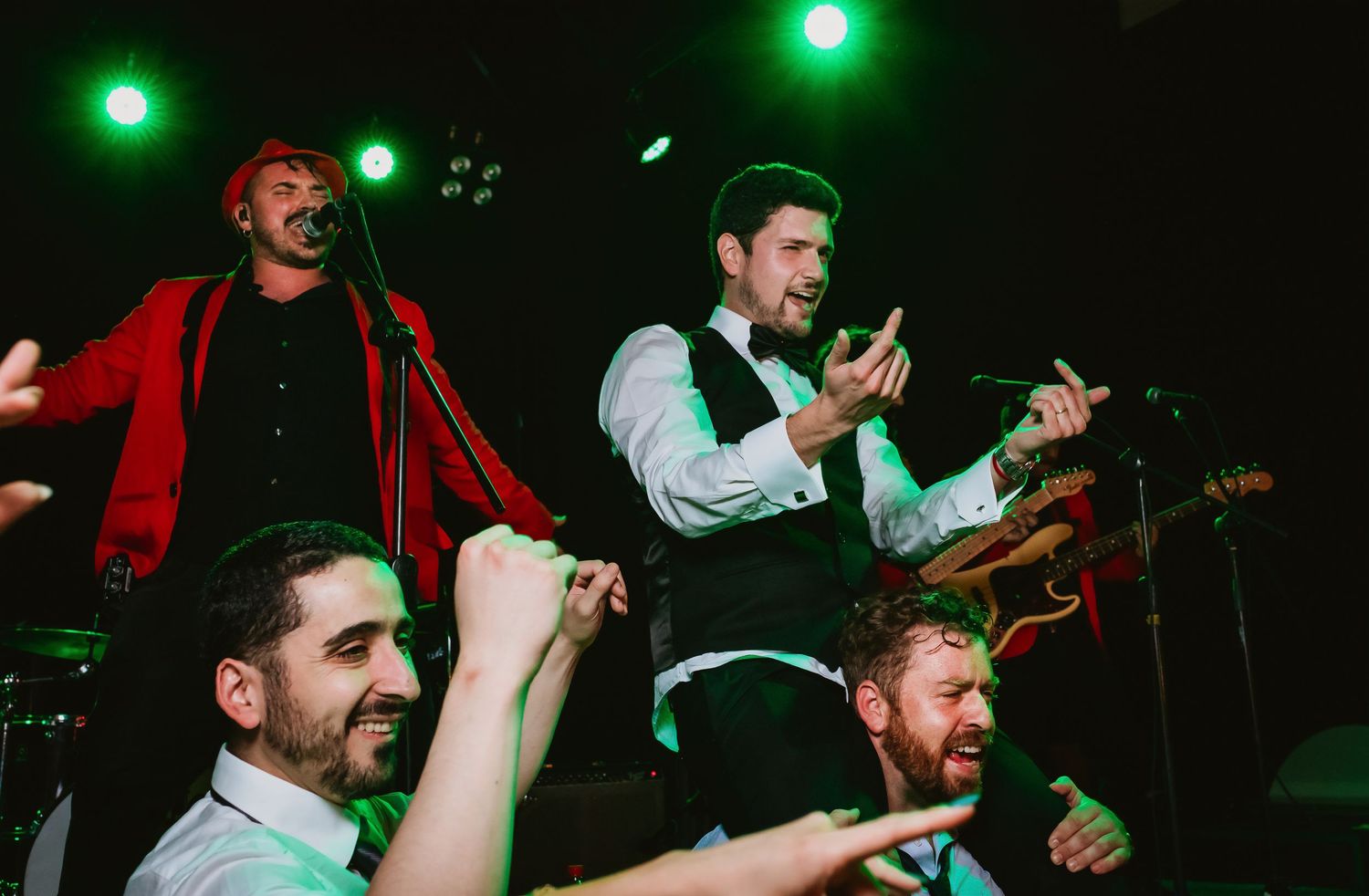 Live band performing energetically on stage at a wedding reception with guests celebrating.