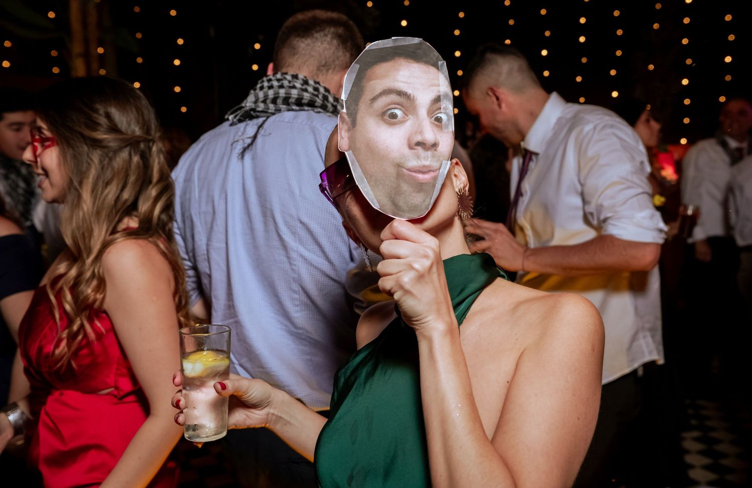 Fun wedding guest wearing a novelty face mask while dancing at a lively wedding reception party.