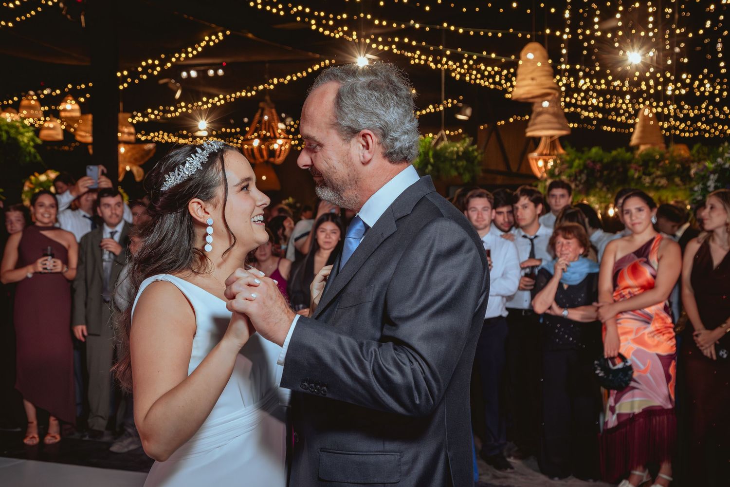 Bride shares a tender father-daughter dance surrounded by guests at wedding reception.