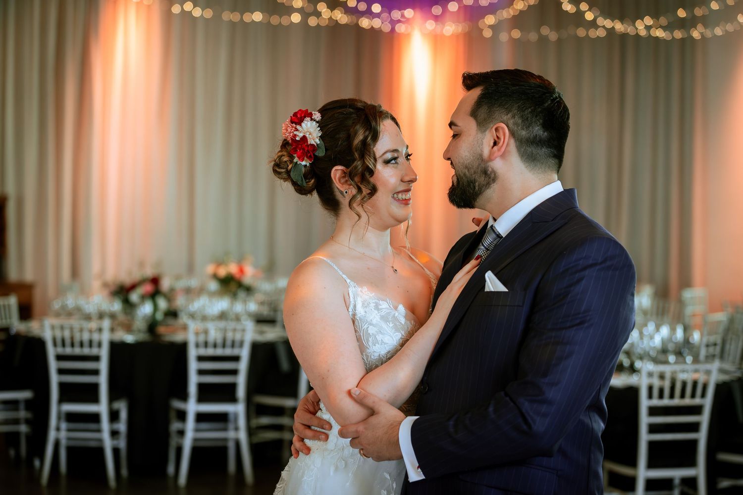 Bride and groom share a romantic dance, gazing into each others eyes at their wedding reception.