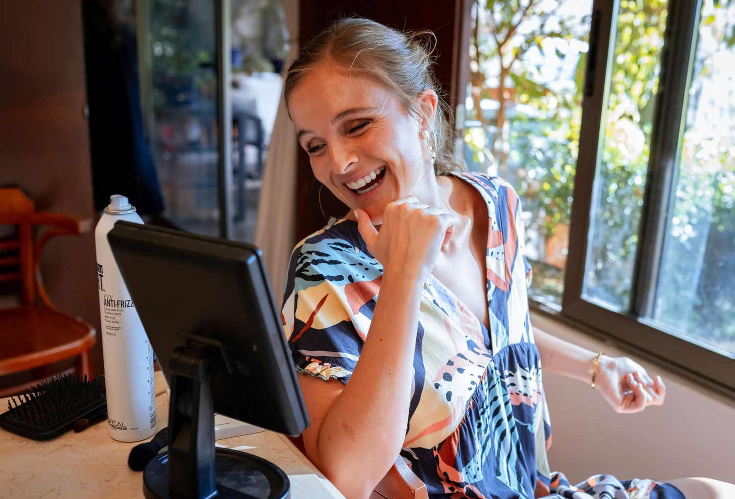 Excited bride-to-be in a floral robe smiling at her reflection during wedding preparations.