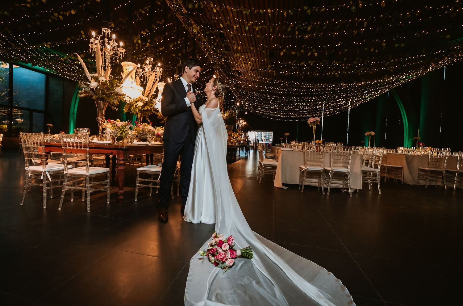 Bride and groom share tender moment under canopy of fairy lights at reception.