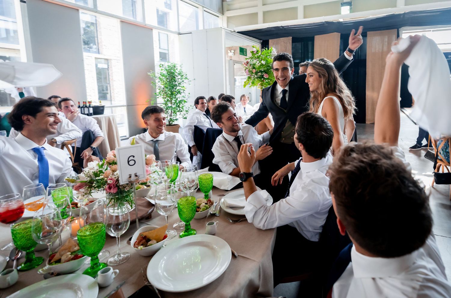 Bride and groom greeting cheering guests at a beautifully decorated wedding reception table.