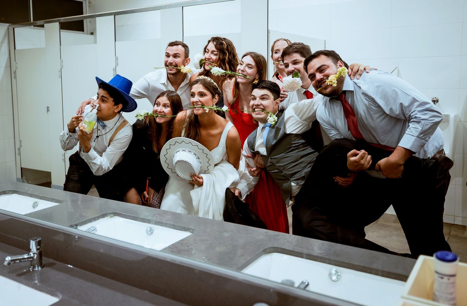 Wedding party takes fun mirror selfie in bathroom during lively wedding celebration.