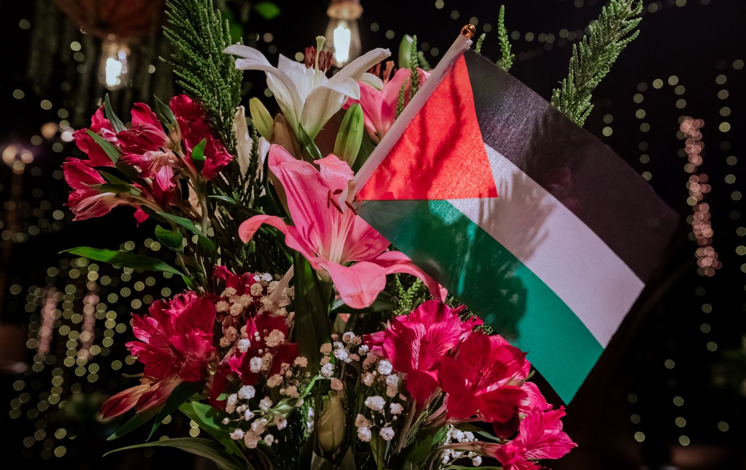 Palestinian flag nestled among vibrant pink and white flowers at a wedding reception centerpiece.