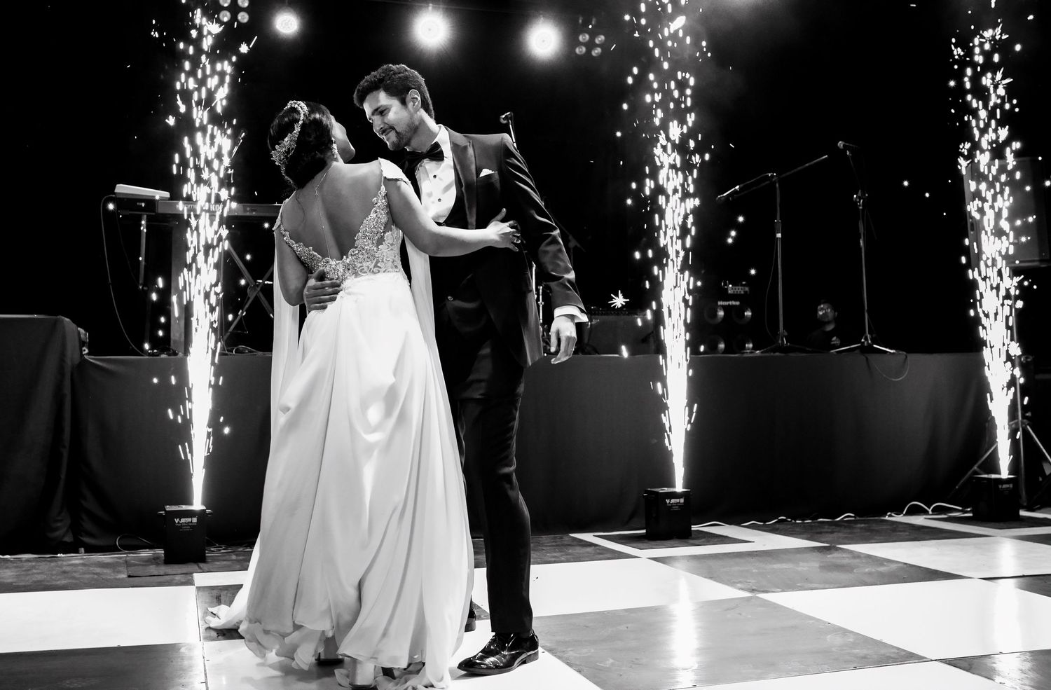 Newlyweds share romantic first dance surrounded by dazzling fountain fireworks at wedding celebration.