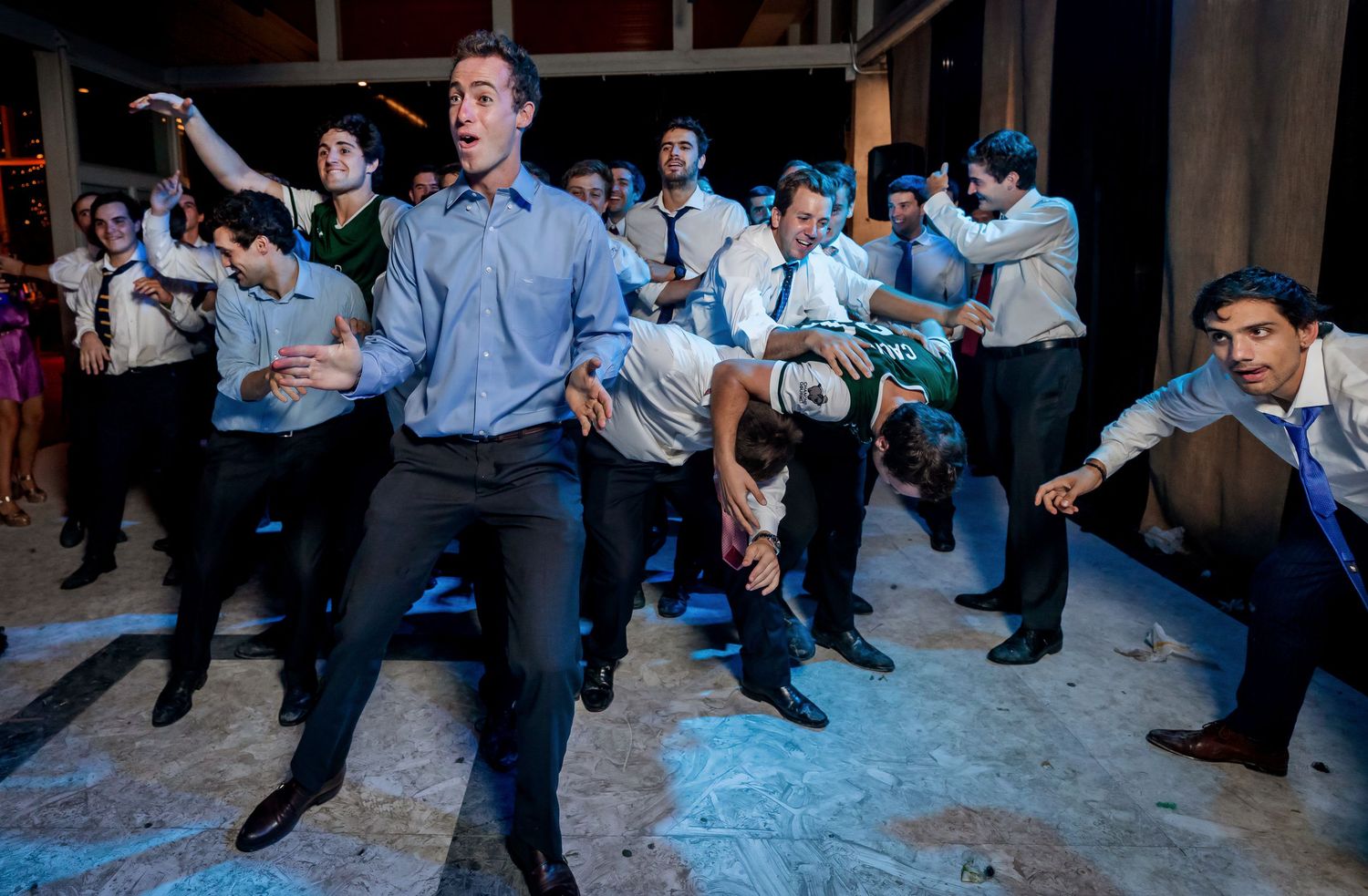 Energetic group of wedding guests dancing together at a lively indoor reception party.