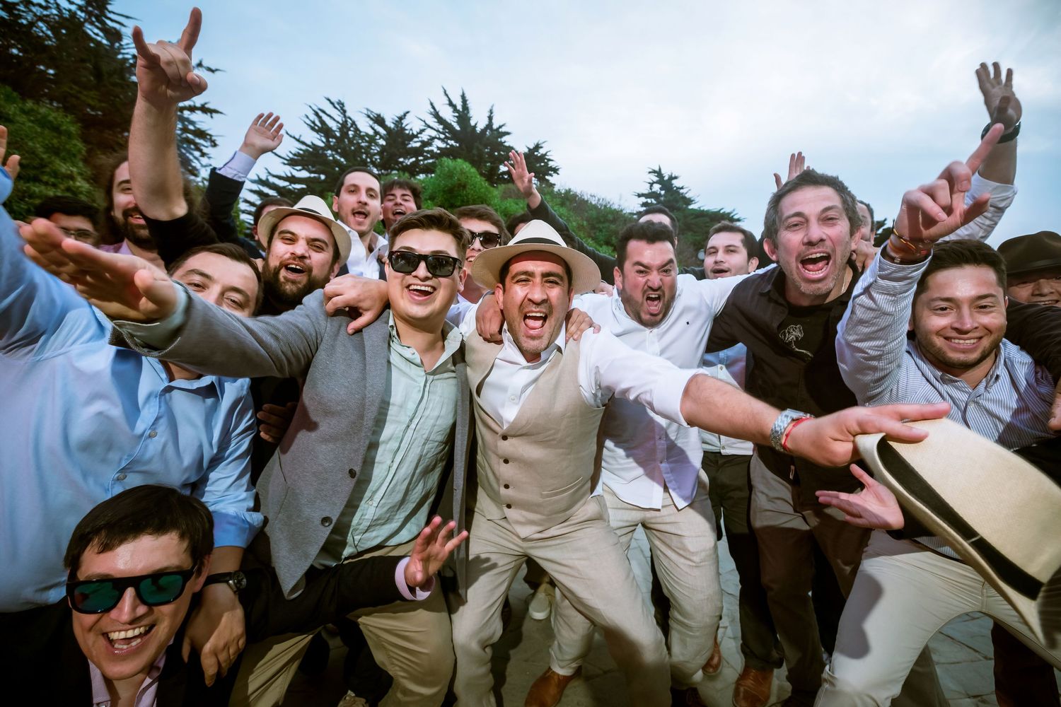 Excited group of young men celebrating at a wedding, laughing and posing together in festive attire.