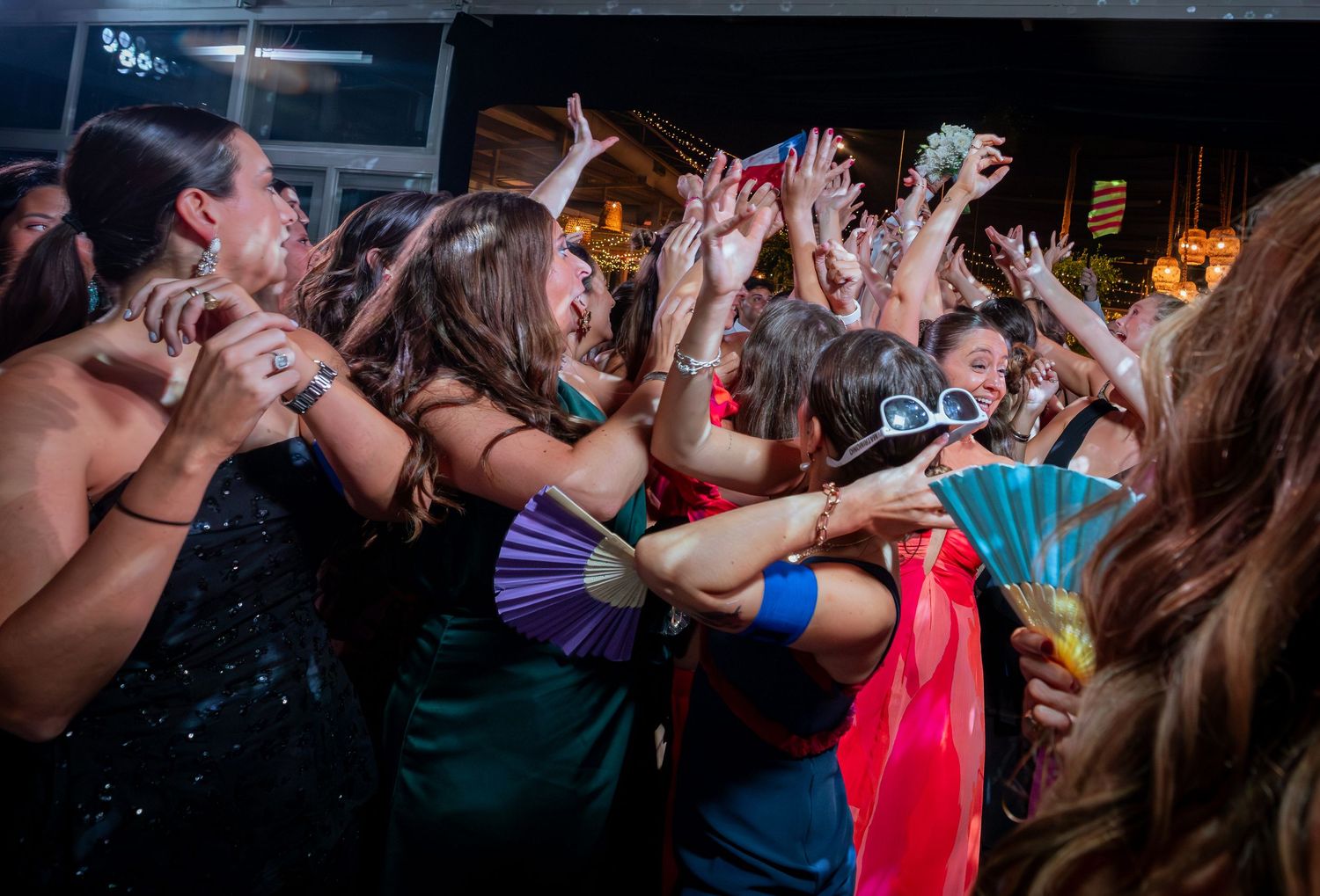 Women guests dance and celebrate with raised hands at lively wedding reception party.