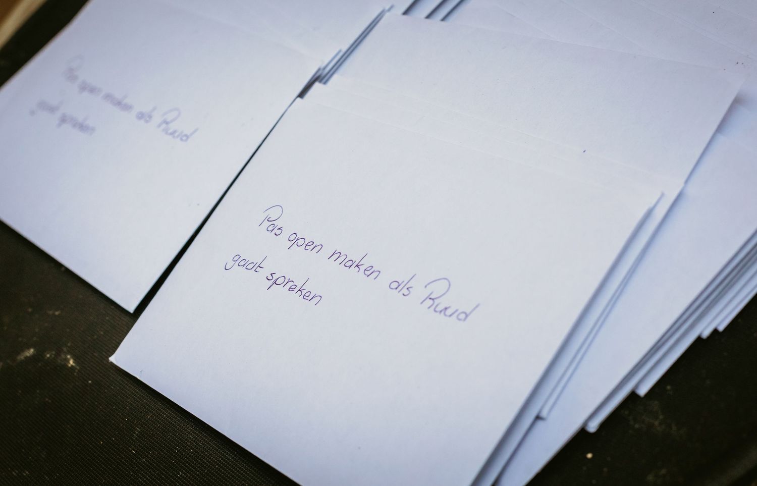 Handwritten notes on white paper cards arranged on dark surface for wedding ceremony.