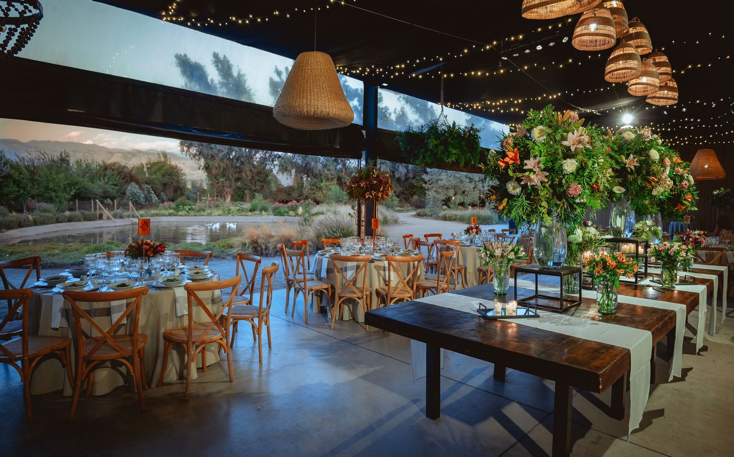 Elegant wedding reception venue with string lights, wooden chairs, and floral centerpieces.