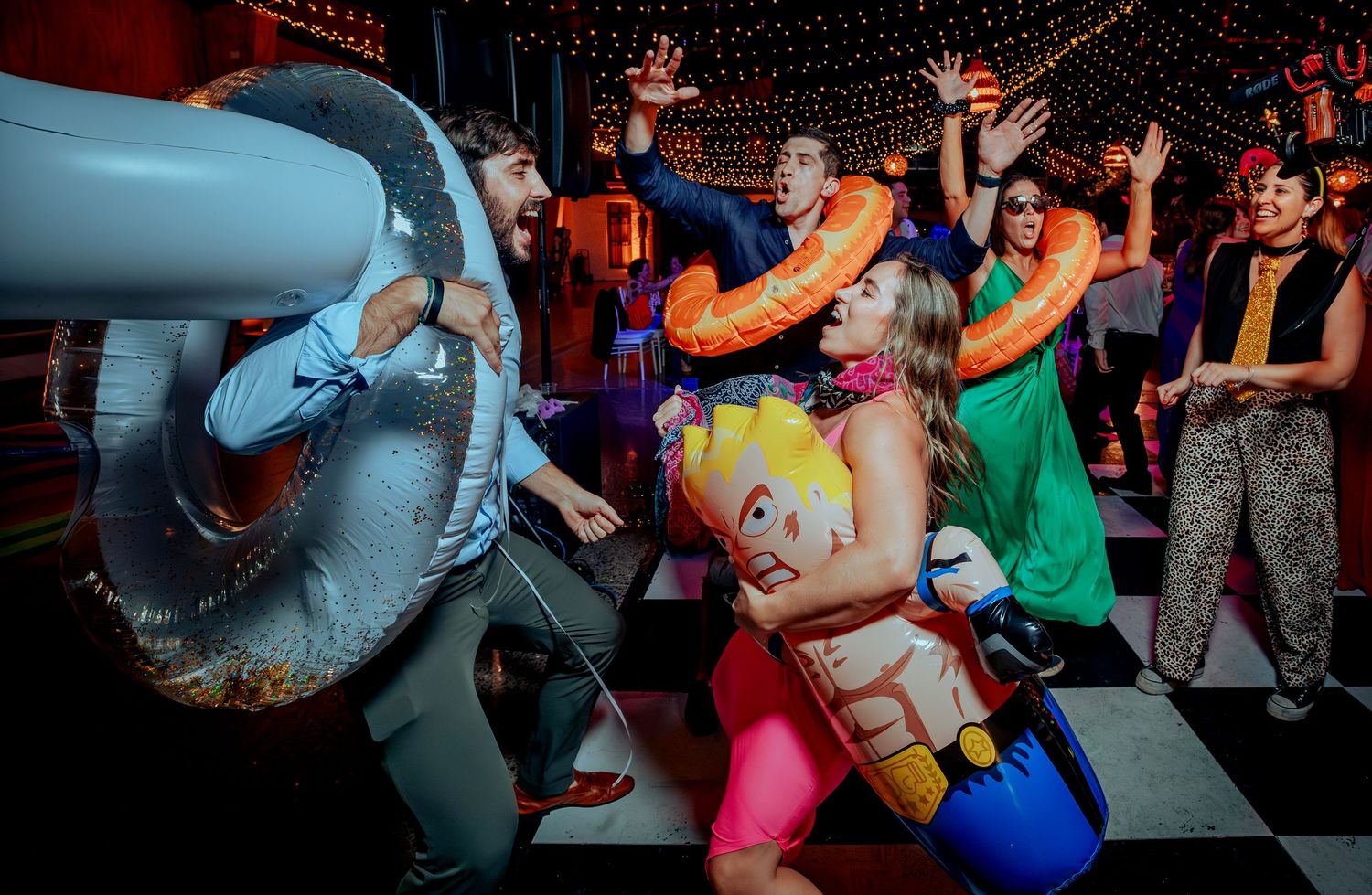 Wedding guests celebrating with inflatable props and pool floats on a dance floor at reception.