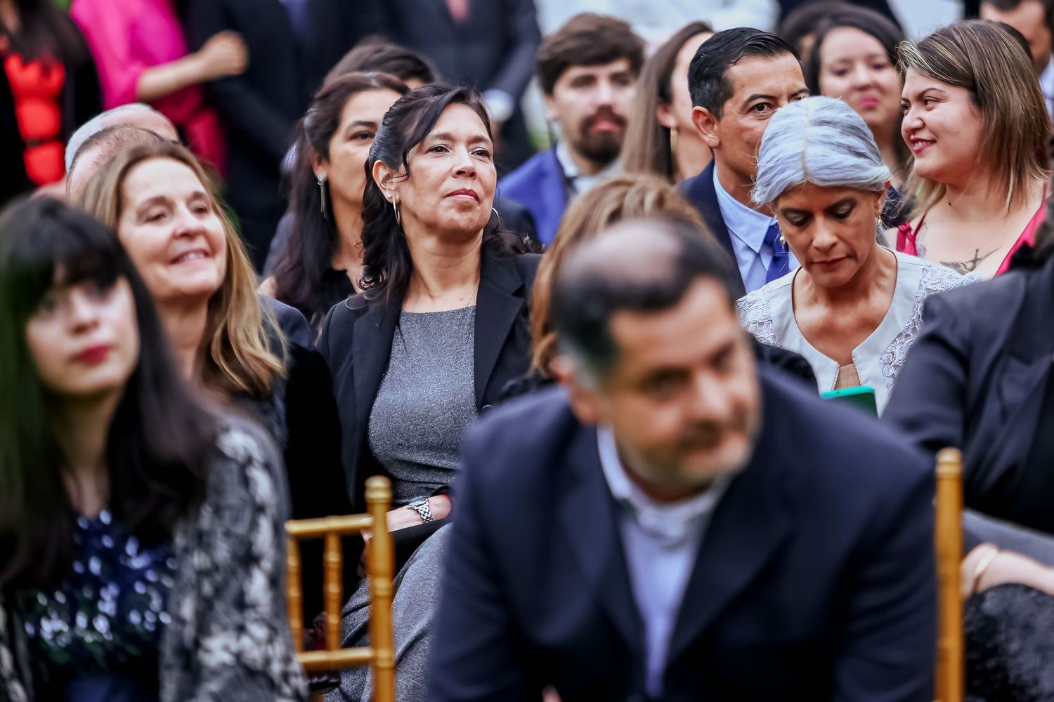 Wedding guests seated outdoors watching ceremony with emotional expressions at elegant daytime celebration.