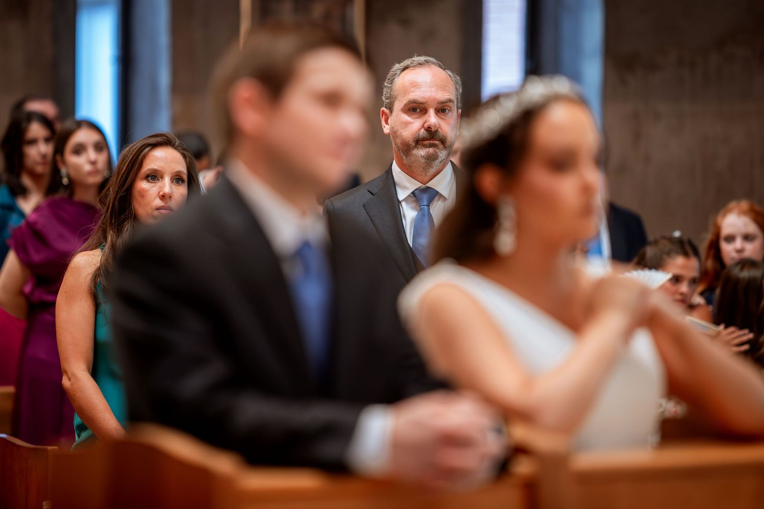 Bearded wedding guest watches the bride and groom during a church wedding ceremony.