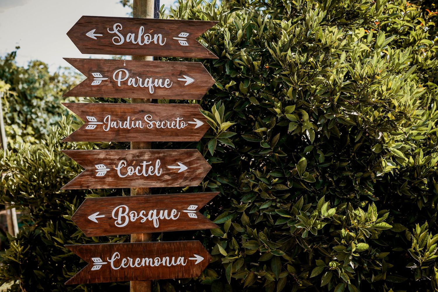 Rustic wooden directional wedding signs pointing to Salon, Parque, Jardin Secreto, Coctel, Bosque, Ceremonia.