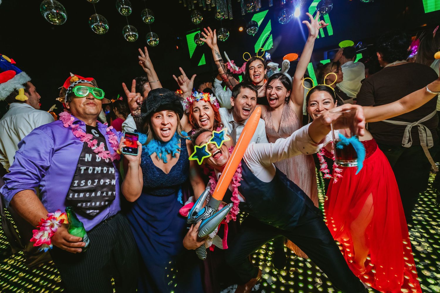 Excited group of friends dancing and posing with neon accessories at a lively party celebration.