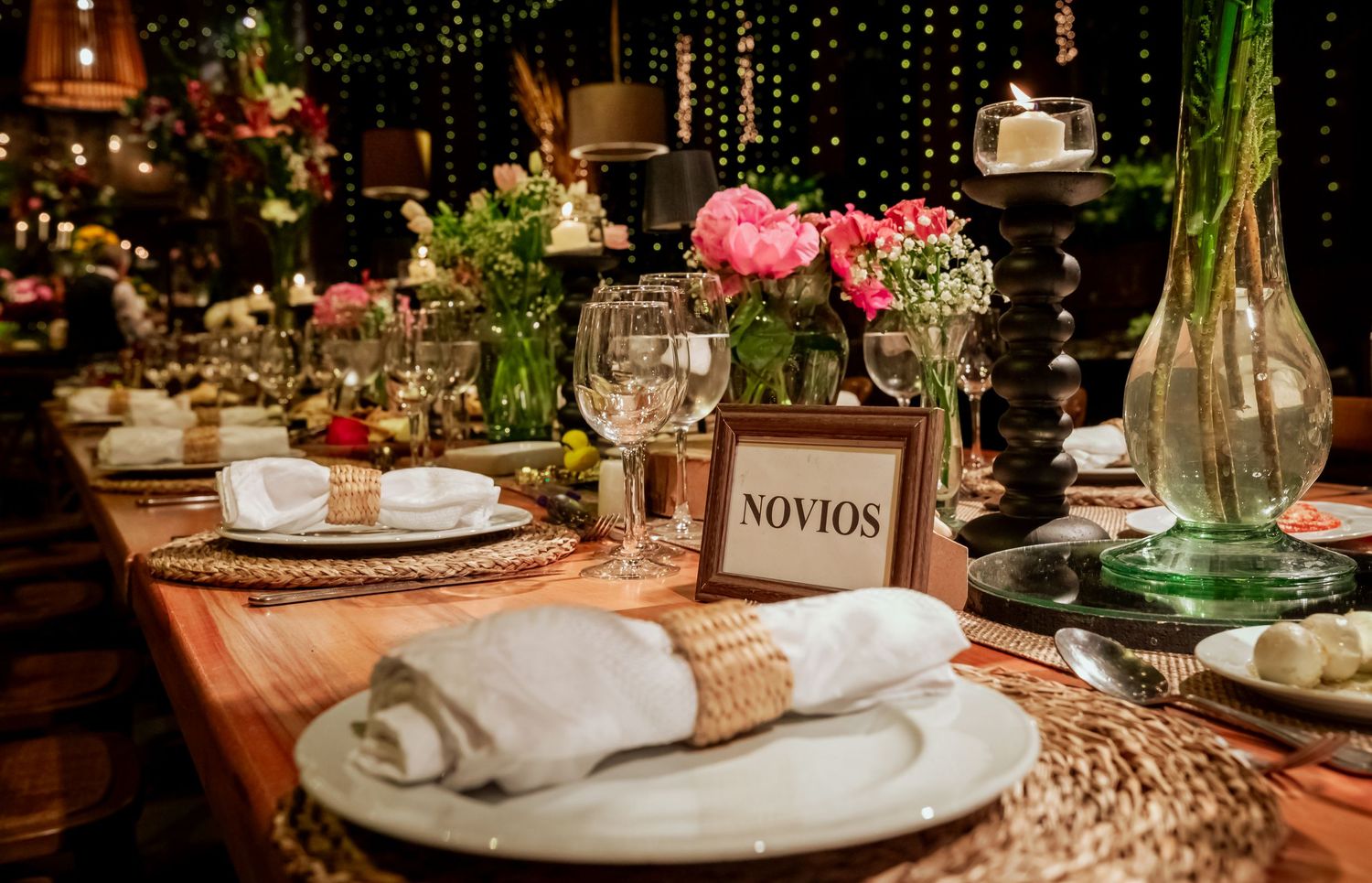 Wedding newlyweds table setting with pink flowers, glassware, and a framed Novios sign.