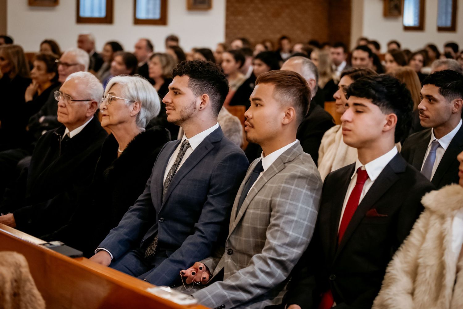 Formally dressed family members seated in church pews during a religious ceremony or service.