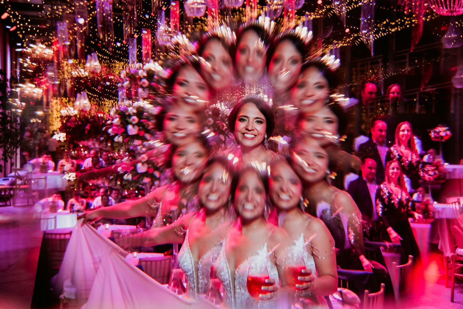 Creative zoom burst photo of smiling bride surrounded by wedding guests in pink light.