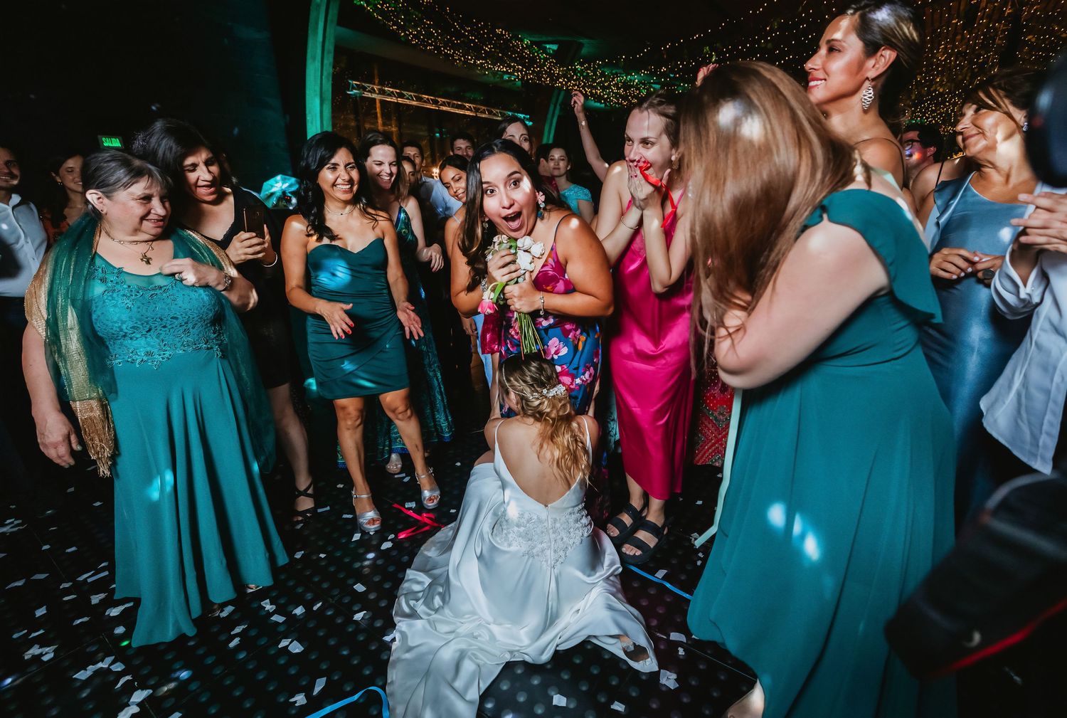 Bride tosses bouquet to eager guests on a confetti-covered wedding dance floor.