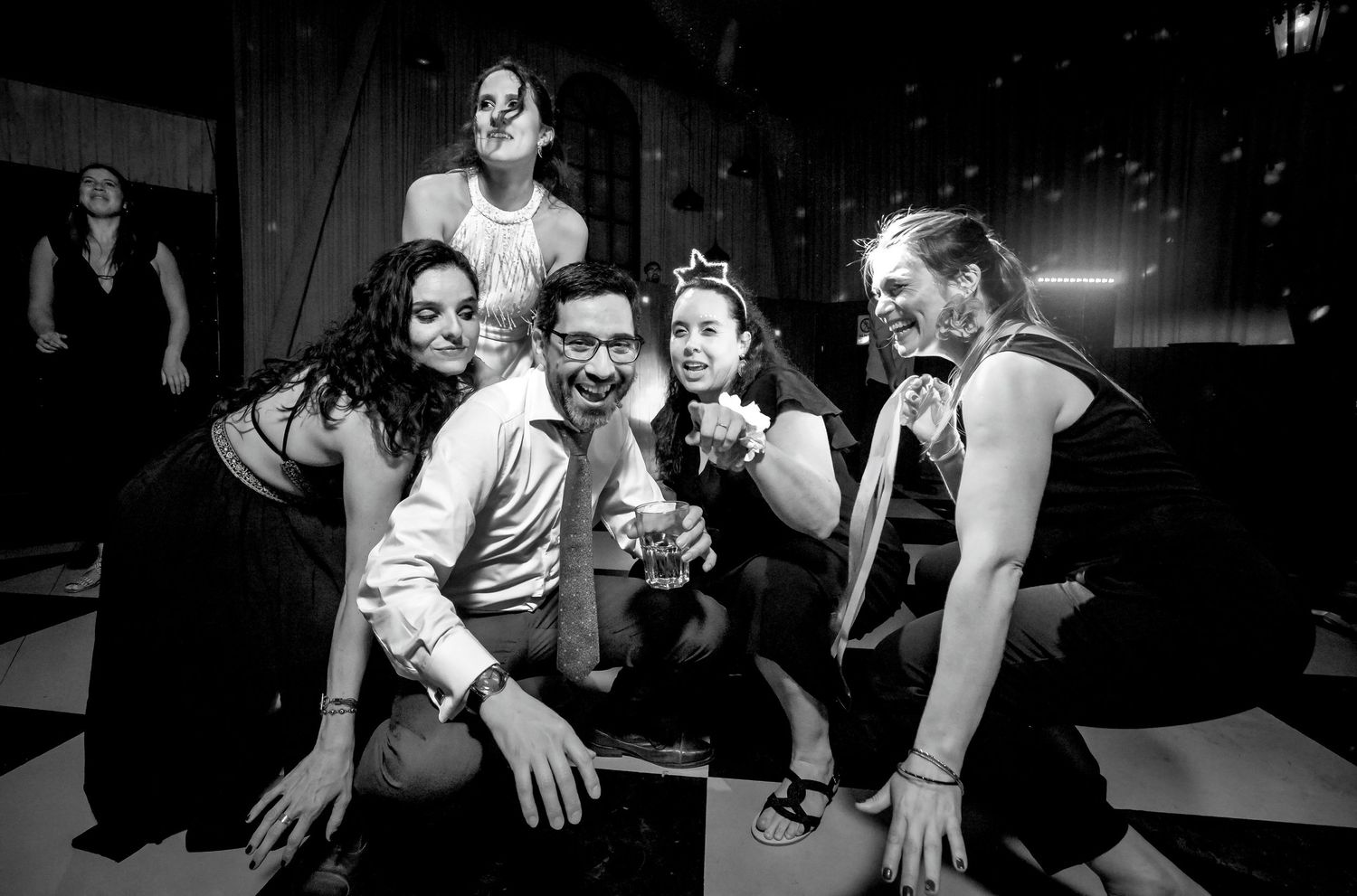 Black and white photo of a man posing with four women on a dance floor at a party.