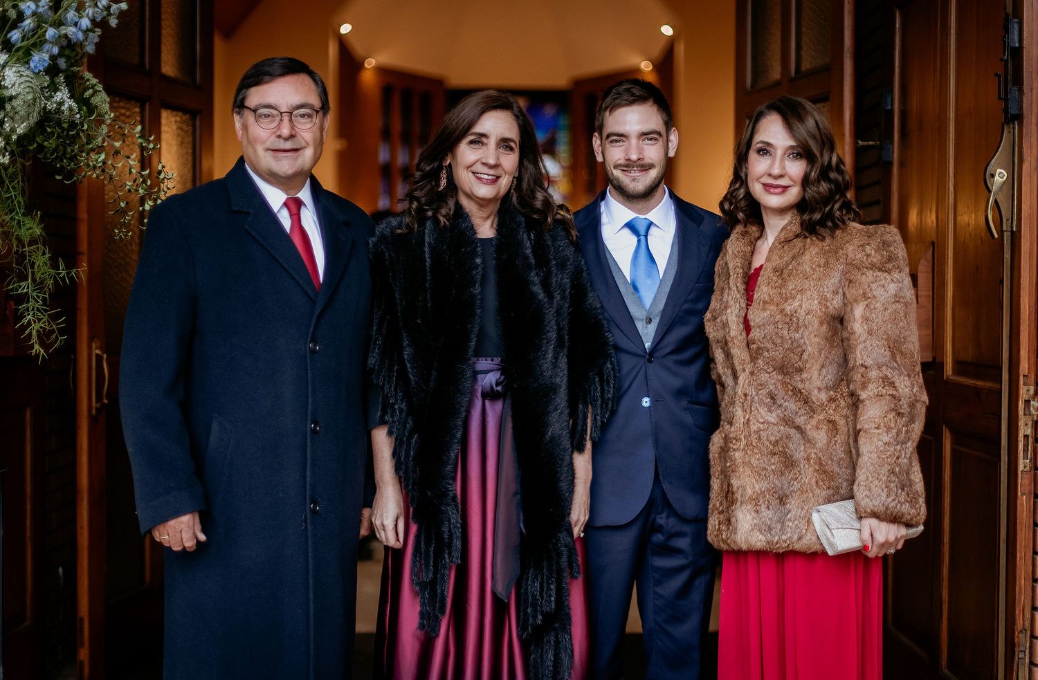 Four elegantly dressed people posing together at a formal event, wearing fur accessories and festive attire.
