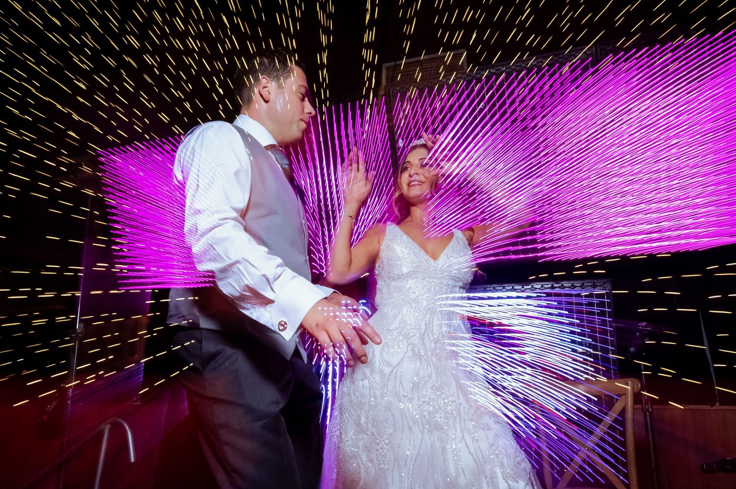Bride and groom share a magical first dance surrounded by dazzling light streaks at their wedding.