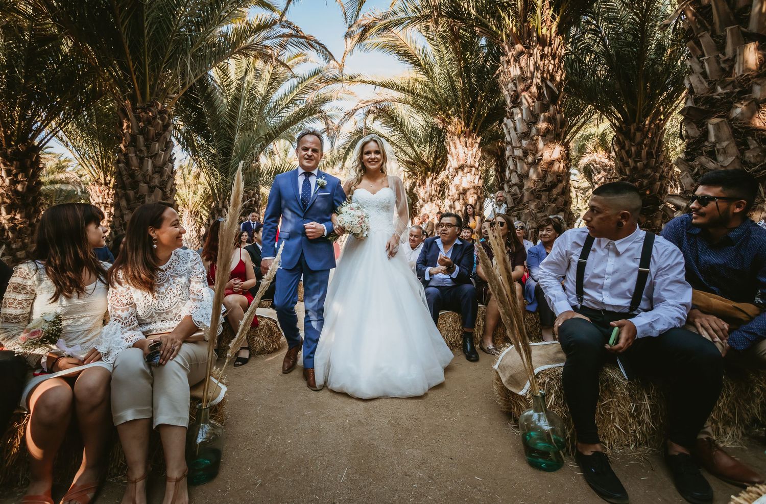 Joyful bride and groom celebrating recessional walk through palm tree wedding ceremony aisle.