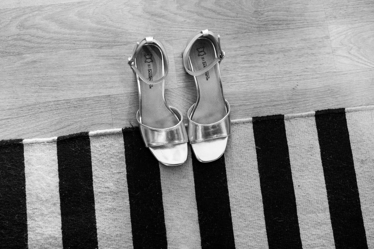Silver strappy bridal sandals on a black and white striped rug, black and white photo.