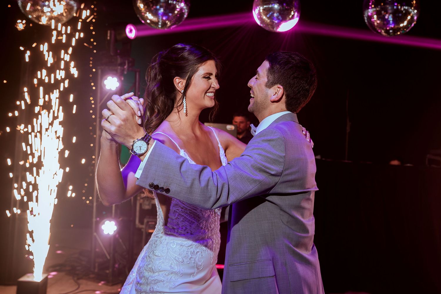 Bride and groom share first dance surrounded by sparkling fireworks and disco balls at elegant wedding reception.