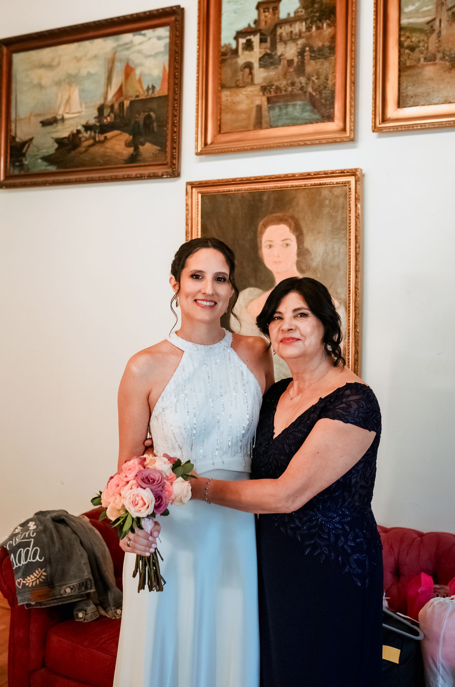 Bride in light blue halter gown holding pink bouquet posing with mother before wedding ceremony.