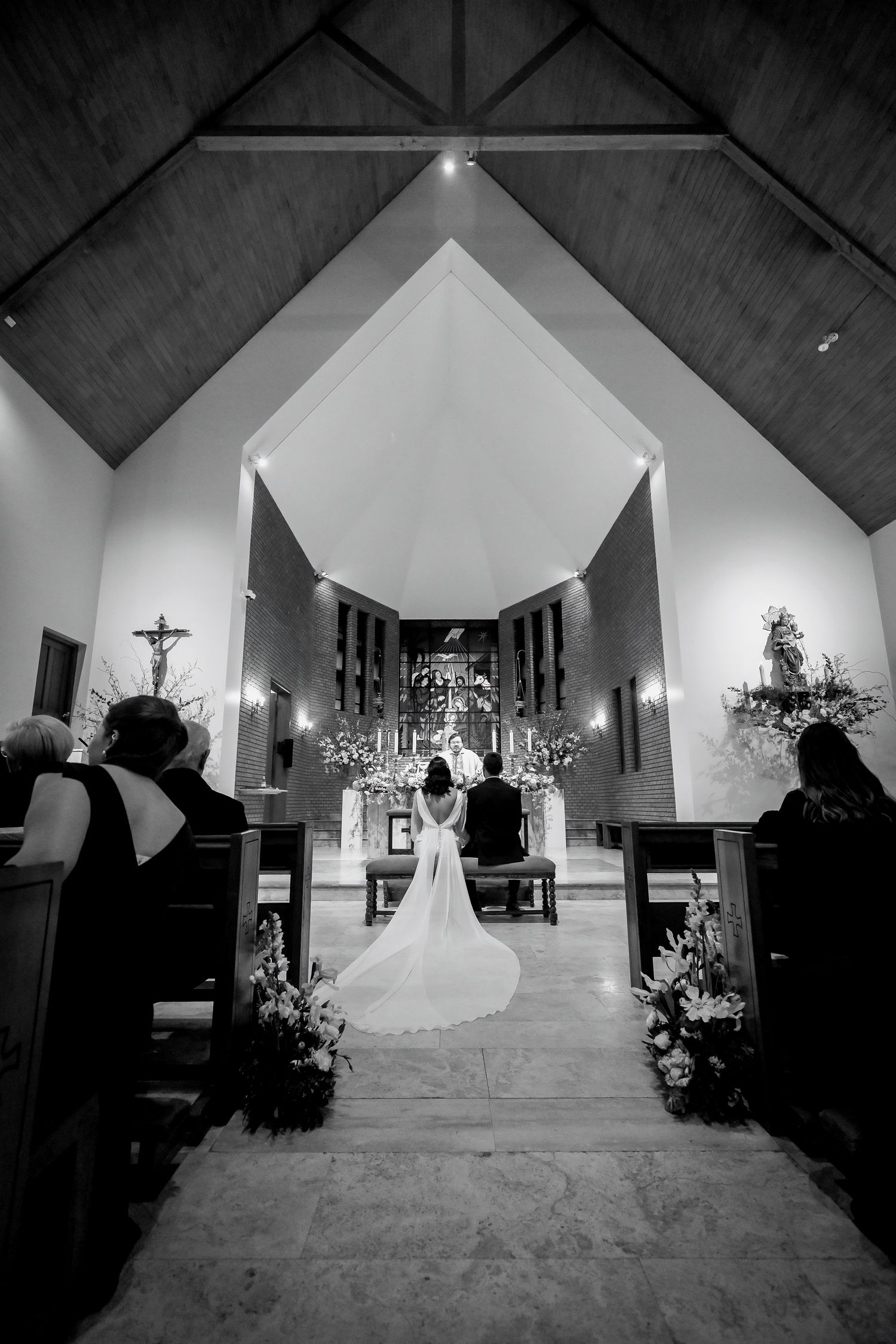 Black and white photo of a bride and groom at the altar of a church during their wedding ceremony.