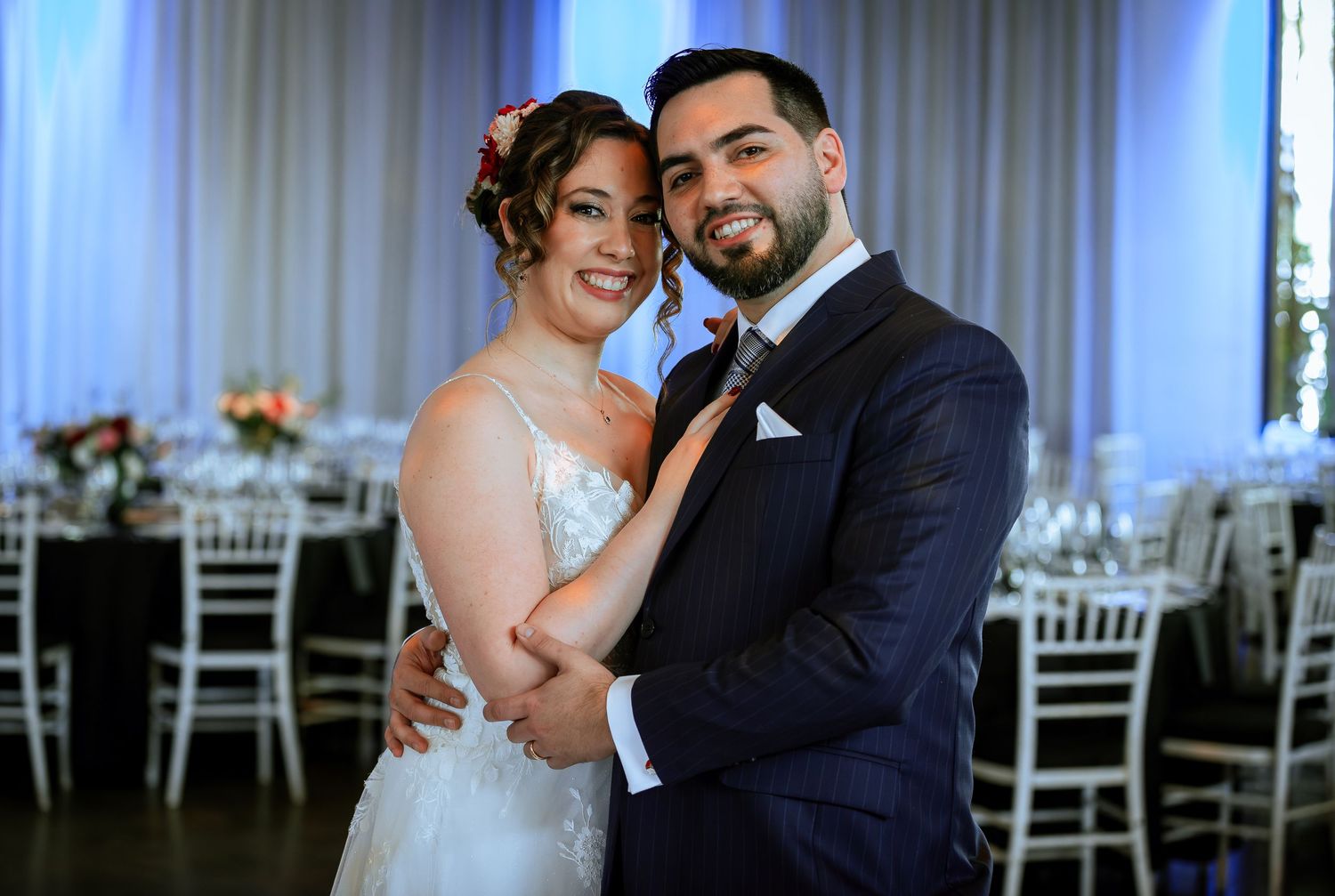 Smiling bride and groom pose together in a beautifully decorated wedding reception venue.