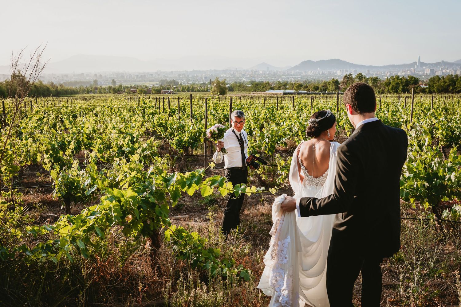 Bride and groom photographed in vineyard with photographer capturing their wedding portraits.