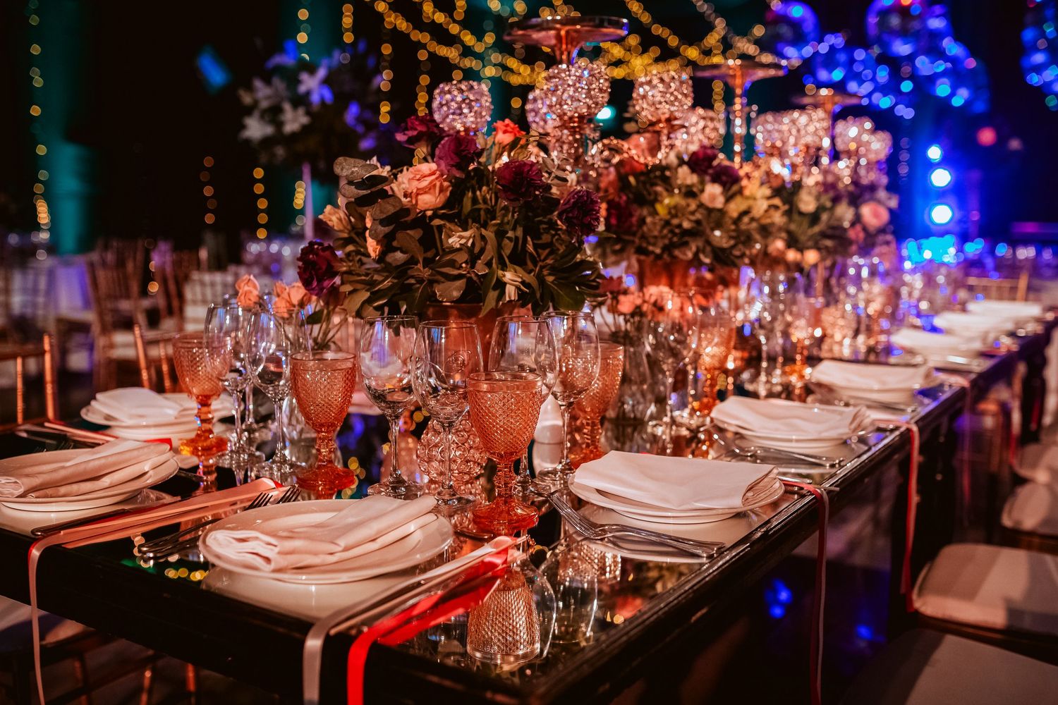 Elegant banquet table with floral centerpieces, crystal glasses, and gold accents at a luxurious event.