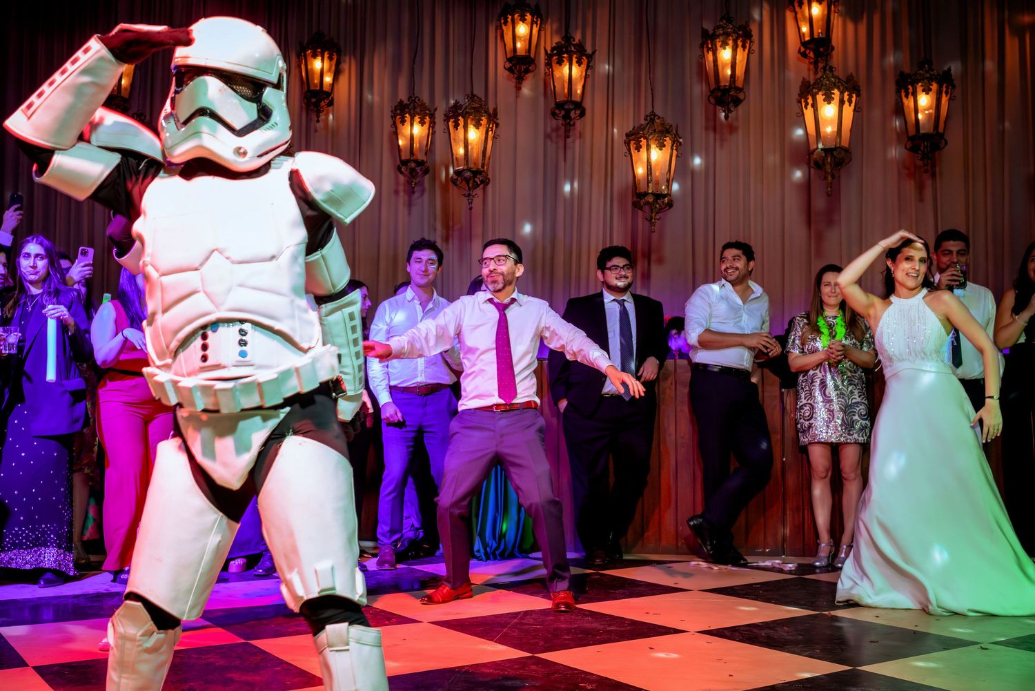 Stormtrooper leading wedding guests in a fun dance on a colorful reception dance floor.