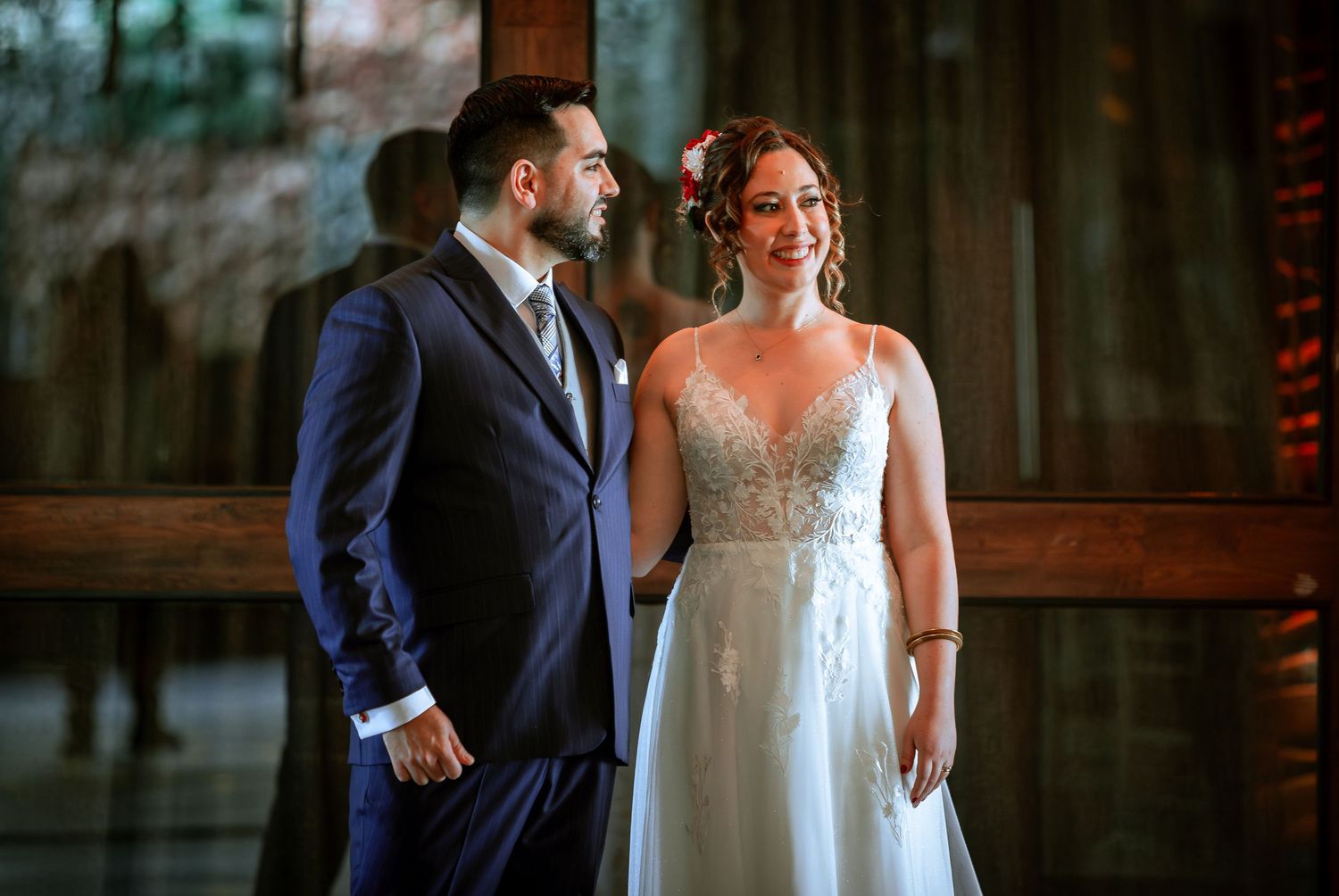Elegant bride and groom stand together near wooden doors during their wedding celebration.