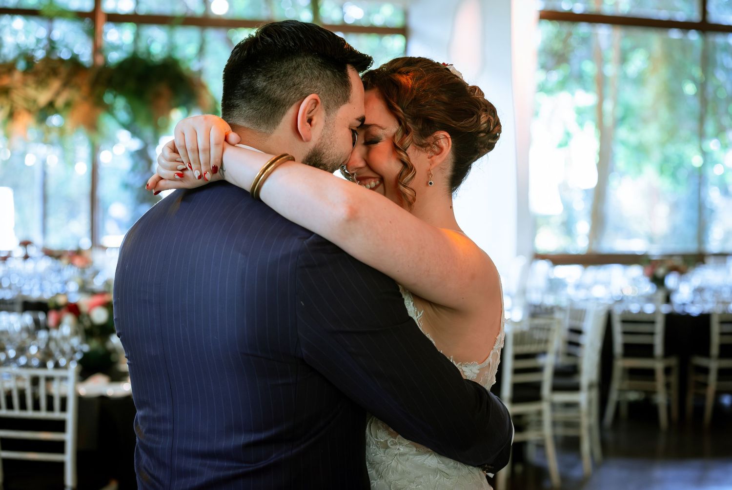 Bride and groom share an intimate close embrace during their first dance at reception.