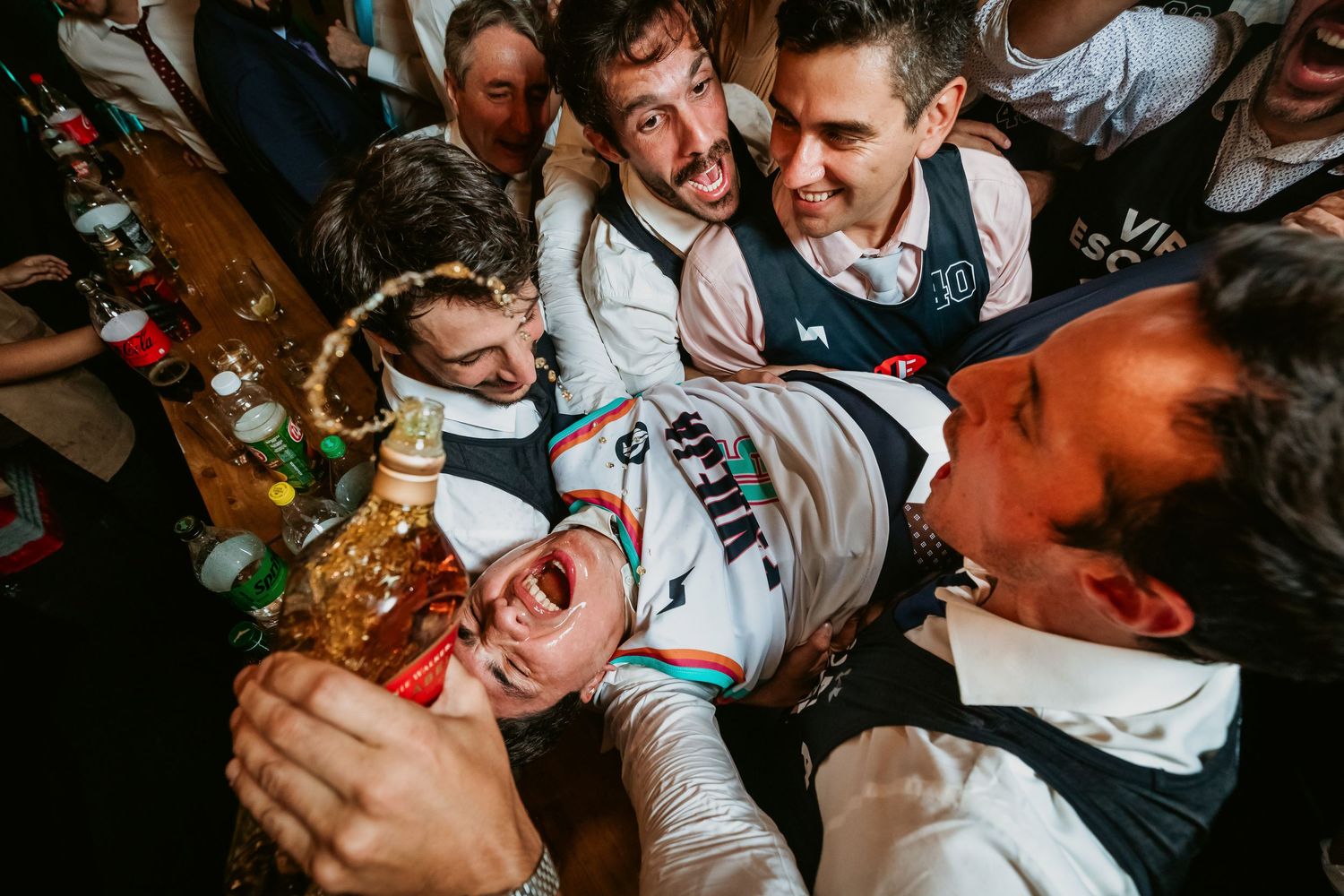 Group of friends celebrating at a lively party, crowd surfing with drinks in hand.
