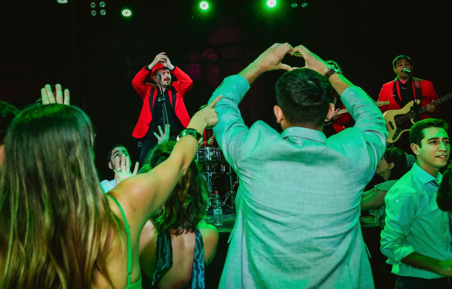 Wedding guests dancing and cheering as a performer in a red jacket entertains the crowd.