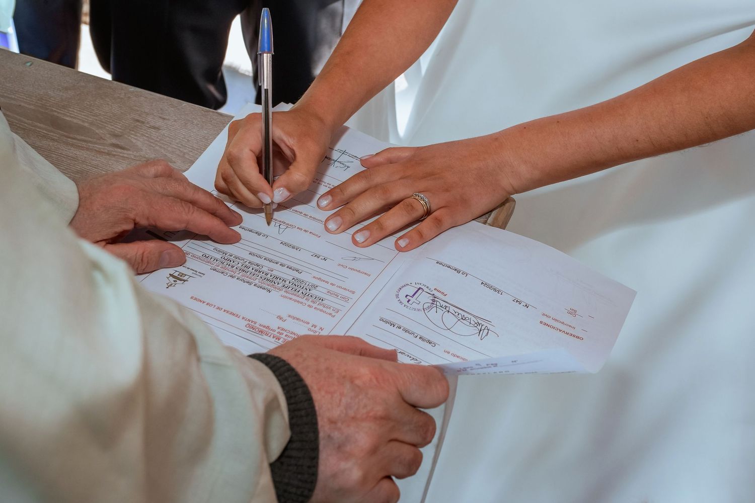 Bride and groom signing official wedding documents with an officiant during their ceremony.