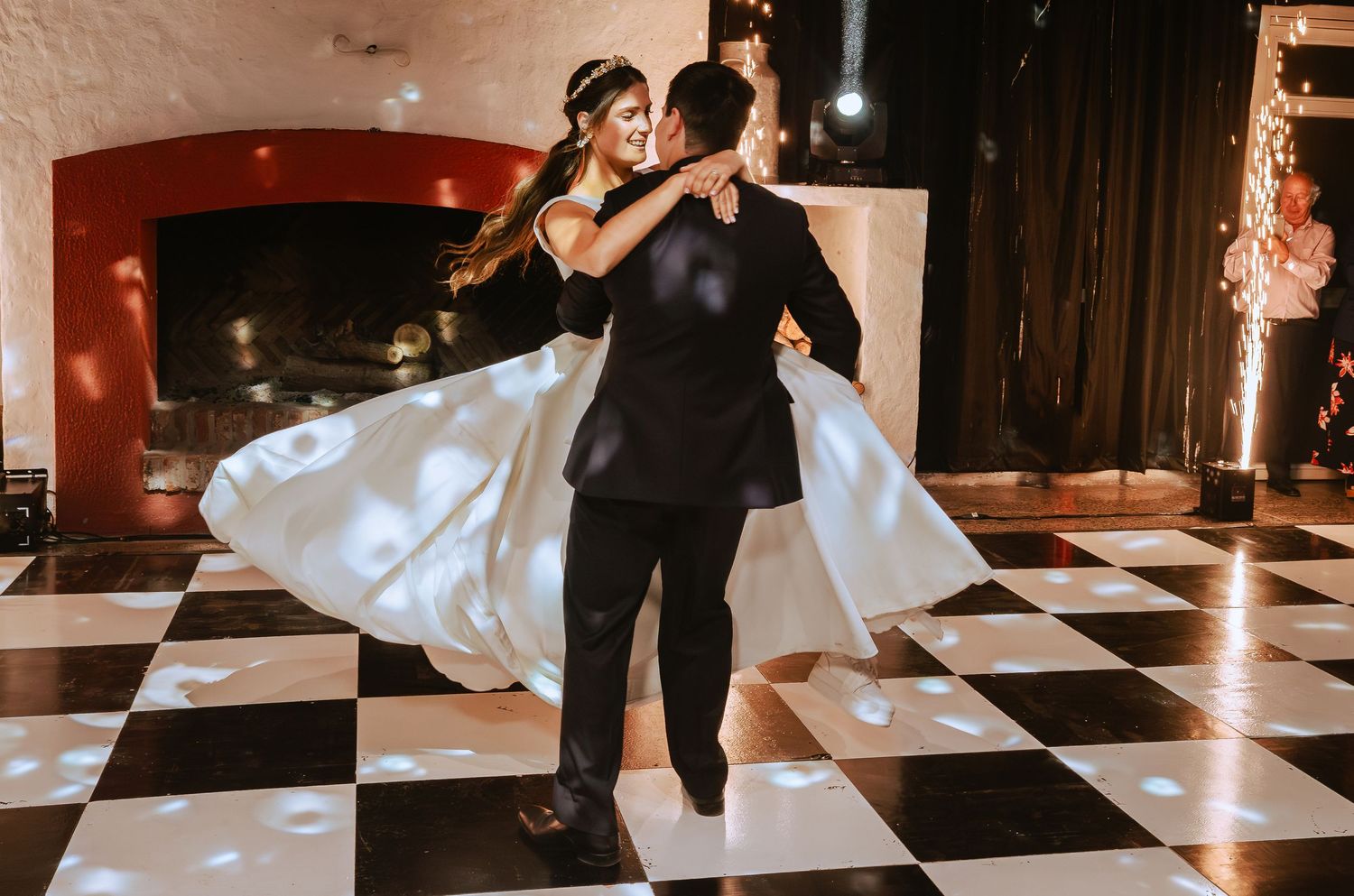 Bride and groom share romantic first dance on black and white checkered dance floor at elegant wedding reception.