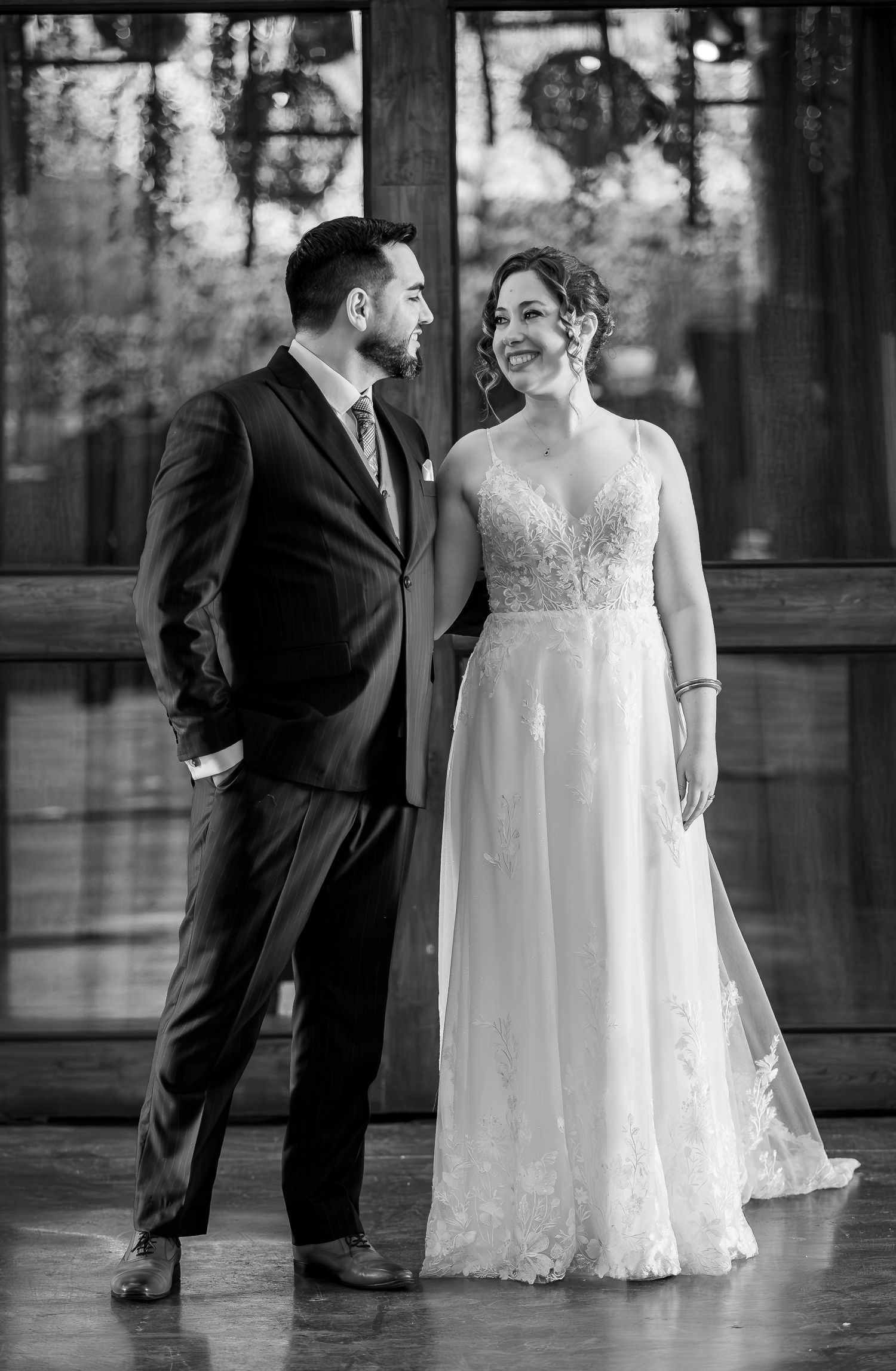 Black and white portrait of a smiling bride and groom standing together at their wedding venue.