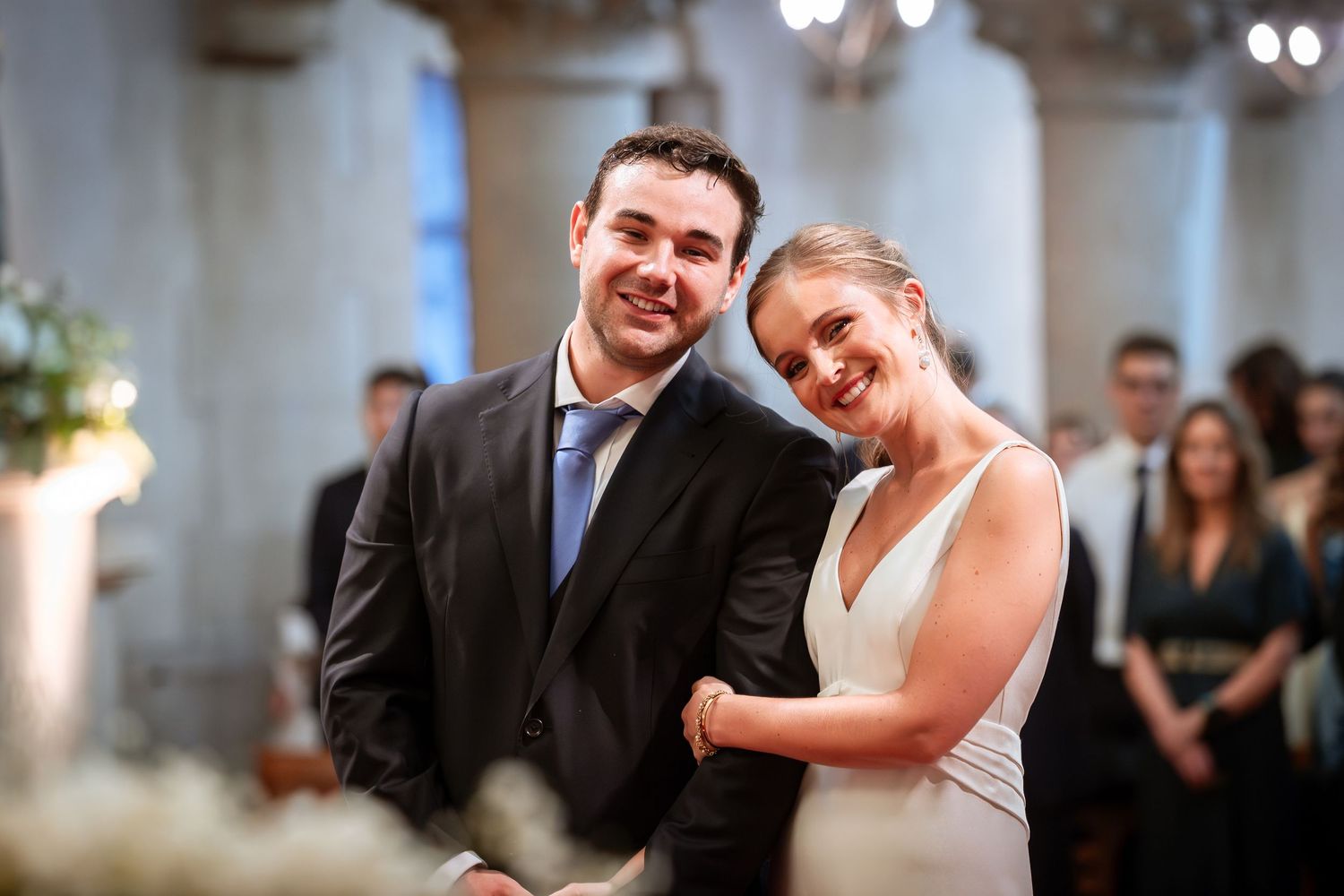 Smiling newlywed couple poses together in church aisle after wedding ceremony.