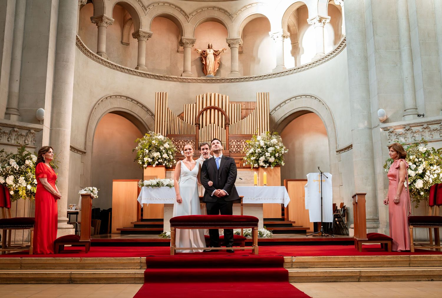 Bride and groom stand at church altar during wedding ceremony with floral decorations.